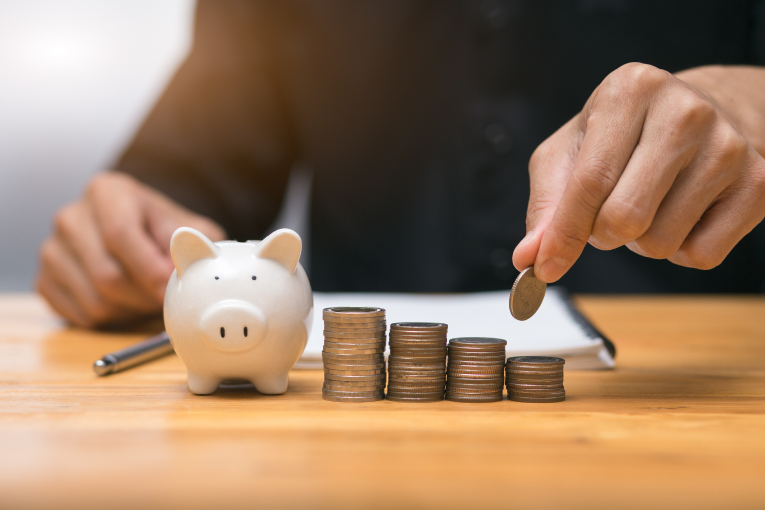 Man stacking quarters next to a piggy bank